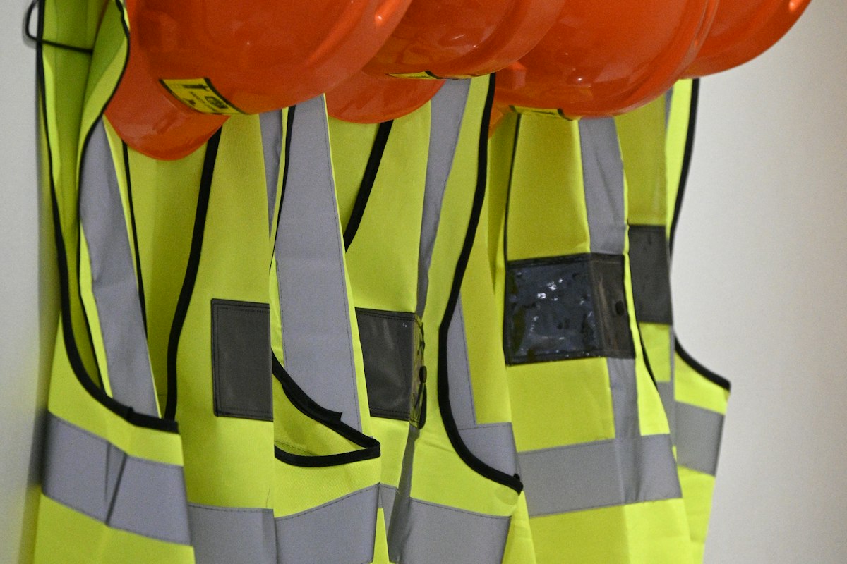 Orange safety helmets and high-visibility vests hanging on a wall